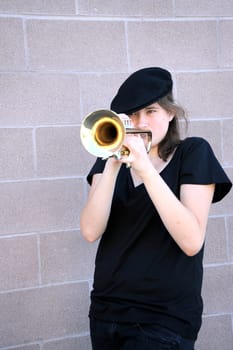 Female trumpet player blowing her horn outdoors.