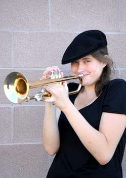 Female trumpet player blowing her horn outdoors.