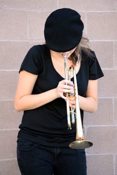 Female trumpet player blowing her horn outdoors.