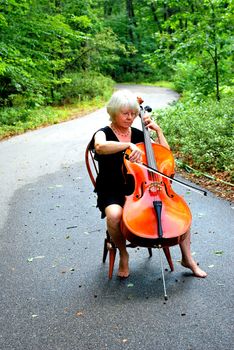 Female cellist posing with her cello outside.