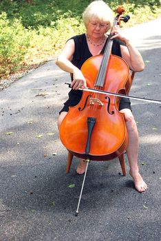 Female cellist posing with her cello outside.