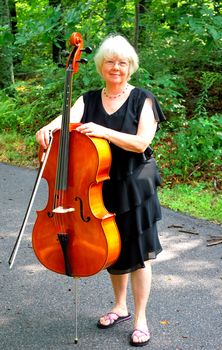 Female cellist posing with her cello outside.