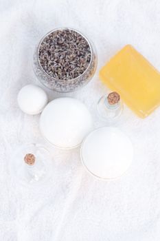 cosmetic containers, bottles, soap and lavender on a white towel