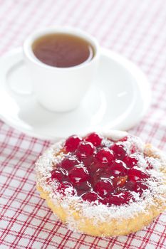 beautiful cake with berries and tea on plaid fabric