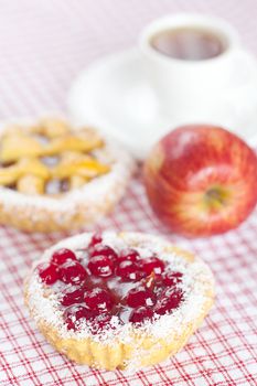 beautiful cake with berries,apple and tea on plaid fabric