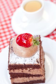 beautiful cake with strawberry and tea on plaid fabric