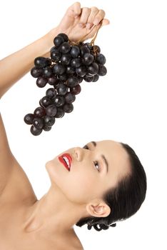 Beautiful sensual brunette eating grapes, isolated on white background
