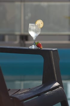 Swimming pool, lounge, a wine glass with ice, lemon and strawberry