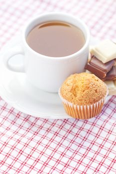 bar of chocolate,tea and muffin on plaid fabric