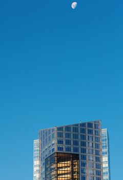 Beautiful modern office buildings and the moon against the blue sky