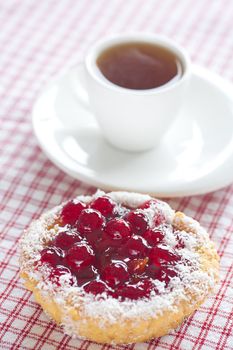 beautiful cake with berries and tea on plaid fabric