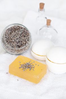 cosmetic containers, bottles, soap and lavender on a white towel