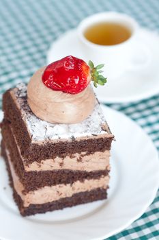 beautiful cake with strawberry and tea on plaid fabric