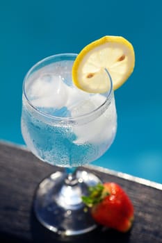 Swimming pool, lounge, a wine glass with ice, lemon and strawberry