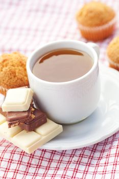 bar of chocolate,tea and muffin on plaid fabric