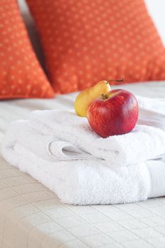 apple and pear on towels on the bed with two pillows