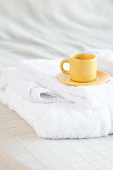 cup lying on towels on the bed 