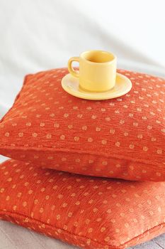 cup lying on pillows on the bed