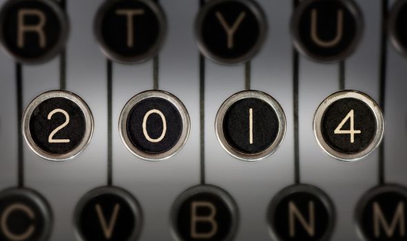 Image of old typewriter keyboard with scratched chrome keys that form "2014". Lighting and focus are centered on "2014". 