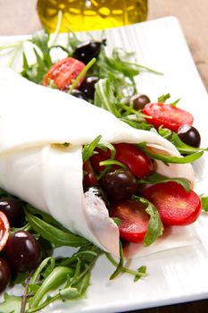 mozzarella roll with tomatoes,olives and salad on wood