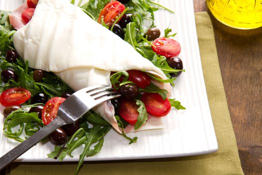 mozzarella roll with tomatoes,olives and salad on wood
