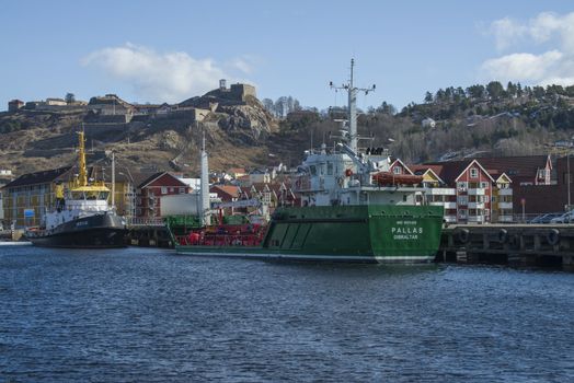 Chemical tanker Pallas and tugboat Hertug moored to the quay at Halden harbor, in the background seems Fredriksten fortress. Halden is a city in Norway. The picture is shot one day in March 2013.