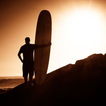 A long boarder watching the waves at sunset in Portugal.