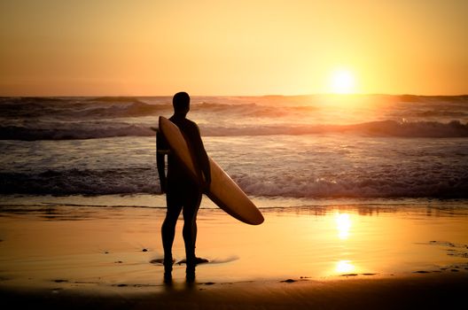 Surfer watching the waves at sunset in Portugal.