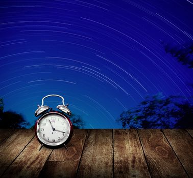 Alarm clock with star trails background. Long exposure concept
