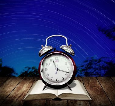 Alarm clock with star trails background. Read for examination