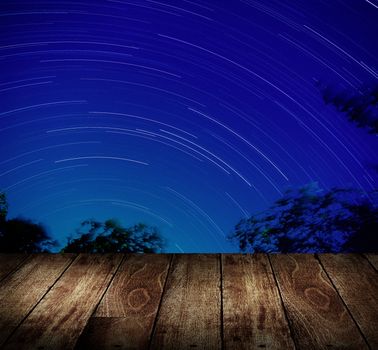 Wooden terrace with star trails background