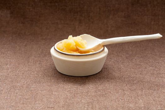 Pot of honey and wooden dipper on a cloth background