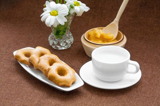 honey cookies, and a vase of daisies on a fabric background