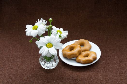 honey cookies in a white plate, and chamomile on a background of burlap