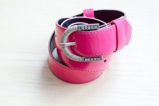 A pink women belts on a light wooden background