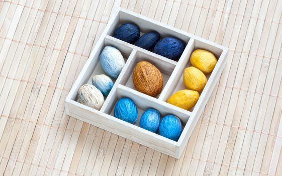 Box with colored nuts on a bamboo napkin