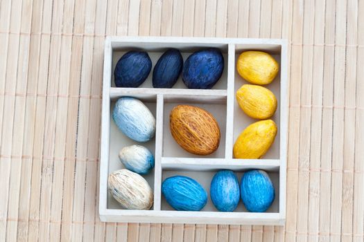 Box with colored nuts on a bamboo napkin