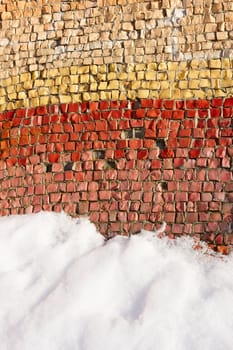 Fragment of an old colortul mosaics partially covered with snow in fine winter day