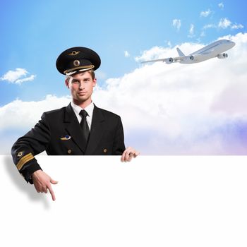 pilot in the form of holding an empty billboard on the background of sky and flying plane, place for text