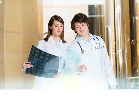 two doctors stand near glowing table discussing. projected objects on a desk