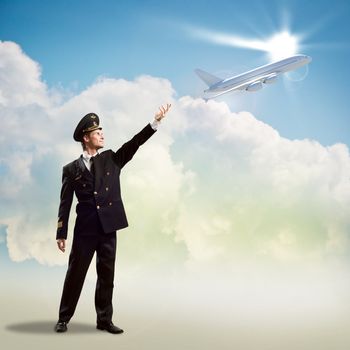 pilot in the form of extending a hand to a flying airplane on the background of clouds and sun