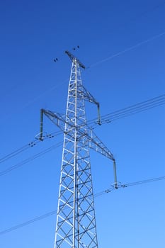 Electrical high-voltage metal pillar against the background of blue cloudless sky