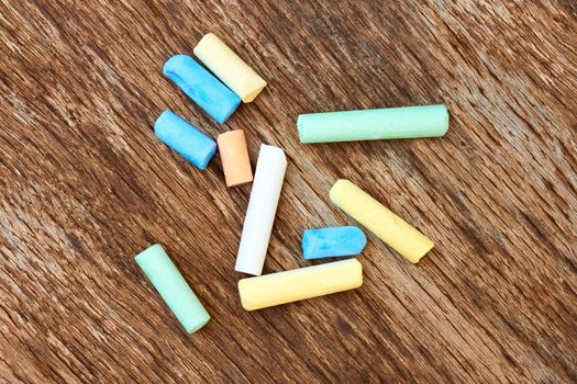 Several cylindrical pieces of colorful chalk on the old eroded brown board