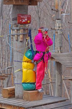 MAGURA, ROMANIA - APRIL 05: Little girl prepairing for zip line in adventure park. Magura Green Park on April 05, 2013 in Magura, Romania