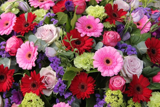 Red and pink gerberas, together with purple roses and other flowers in a wedding arrangement