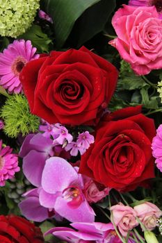 red and pink roses, pink orchids and gerberas in a floral arrangement