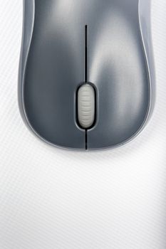 A wireless mouse positioned vertically on the cover of a laptop