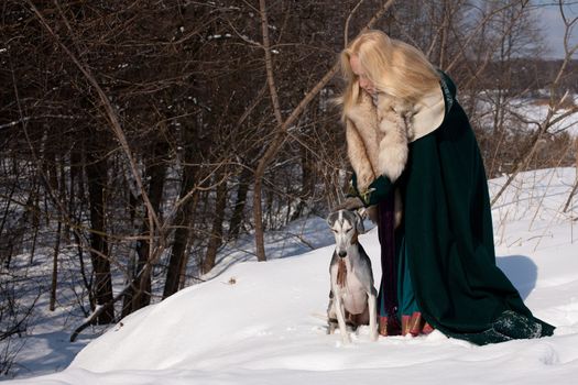A blonde girl and a grey saluki on snow
