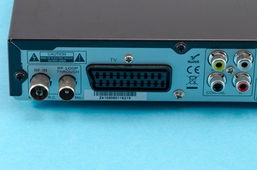 dvb-t tv receiver back side scart and tulip wire and antenna aerial connection sockets on blue background.