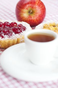 beautiful cake with berries,apple and tea on plaid fabric